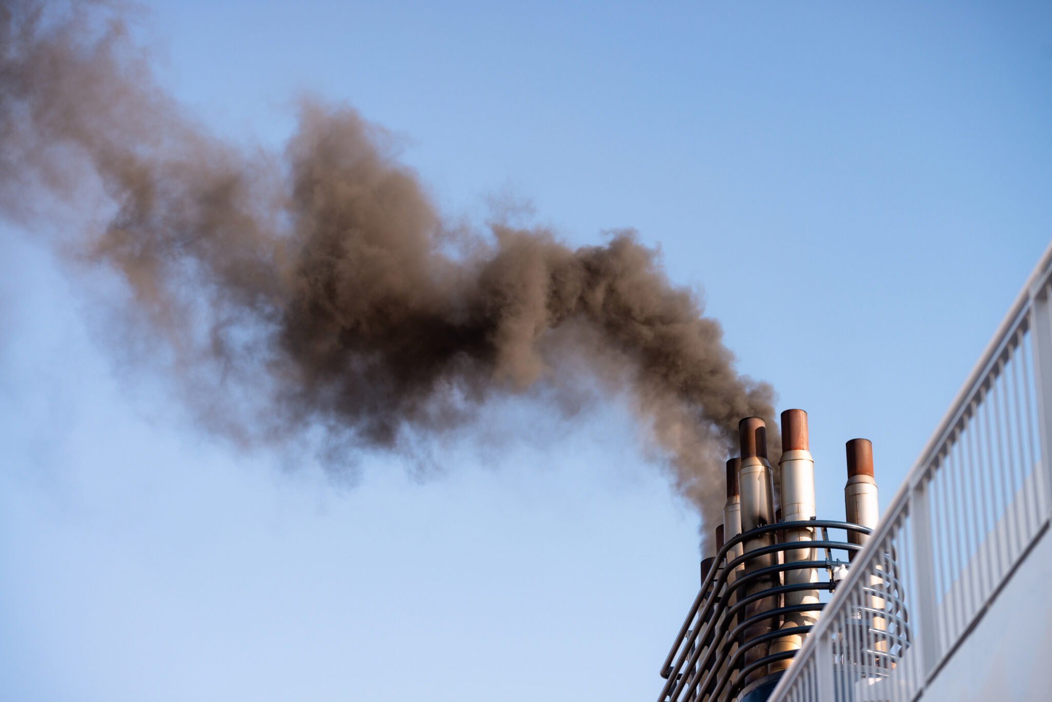 A thick plume of dark smoke coming from the funnels of a large ferry while manoeuvring.